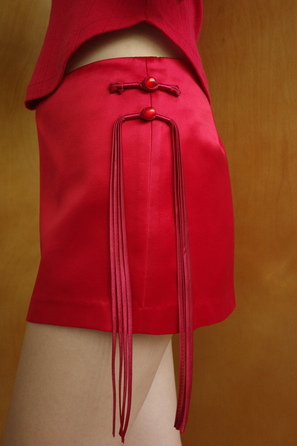 Side view of The Lucky Set Skirt – red rouleau cords falling from a knotted pankou at the hip