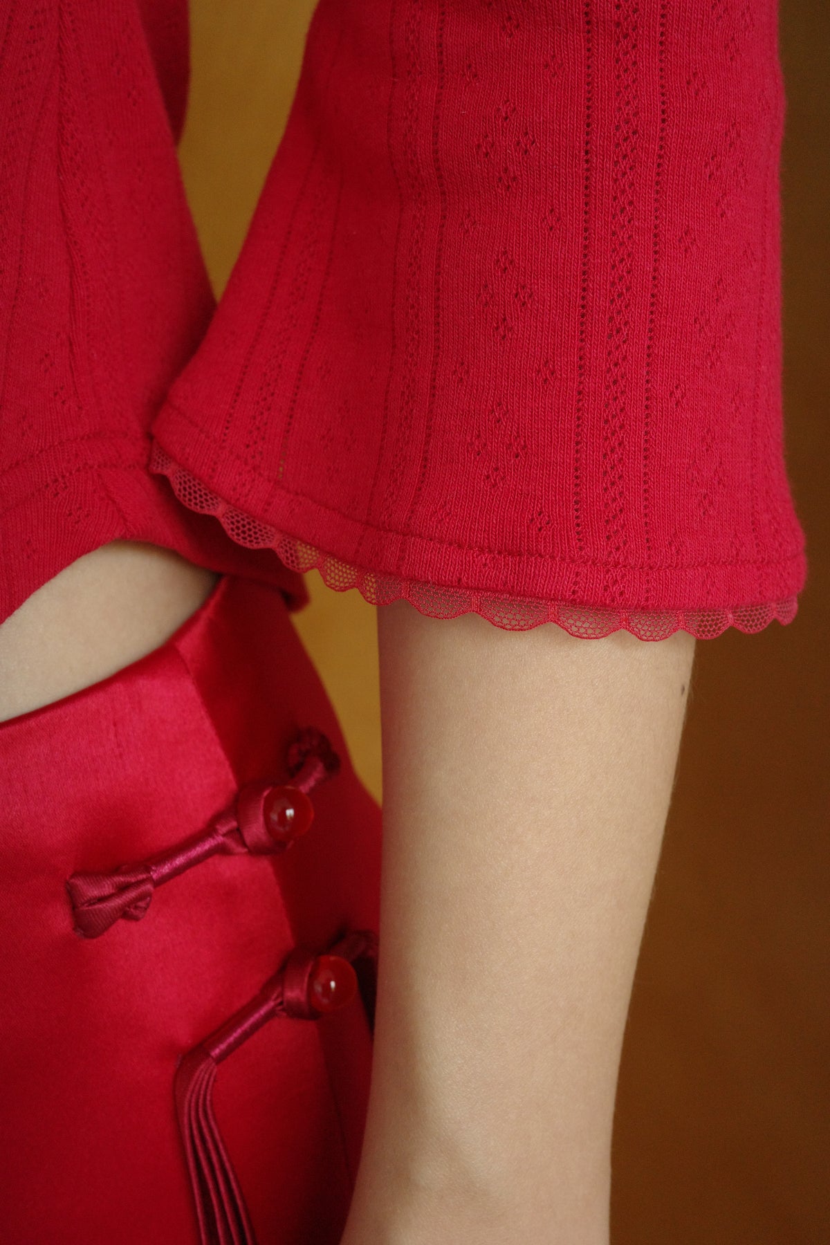 Detail of The Lucky Set Top sleeve – red pointelle bell cuff finished with scalloped tulle trim